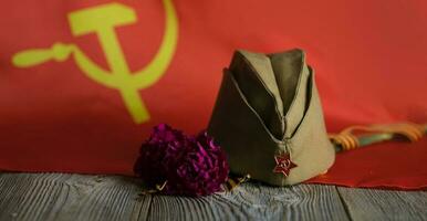 Military cap, carnations, Saint George ribbon on a wooden surface. photo