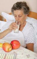 Old woman drinks some milk in the morning photo