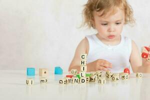 pequeño niña compone palabras desde letras. de cerca foto