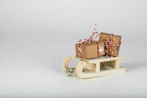 pequeño decorativo de madera trineo con Navidad regalos en un gris antecedentes. foto