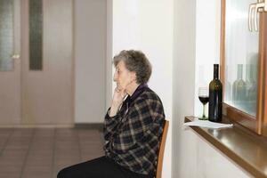 Old woman of 80 years old stays close to the window photo