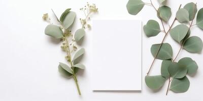 Minimalist Greeting Card Mockup with Delicate Dry Eucalyptus Leaves - Top View on a Clean White Background, photo