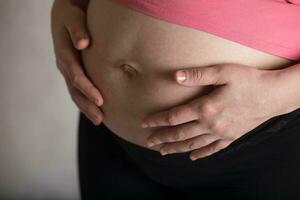 Young pregnant woman touches her belly. Dramatic light. photo