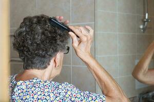 Old woman is combing her hair photo