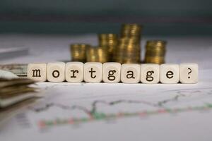 Word MORTGAGOR composed of wooden letter. Stacks of coins in the background. photo