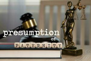 Words PRESUMPTION of PATERNITY  composed of wooden dices. Wooden gavel and statue of Themis in the background. photo