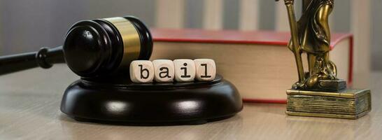 Word BAIL composed of wooden dices. Wooden gavel and statue of Themis in the background. photo