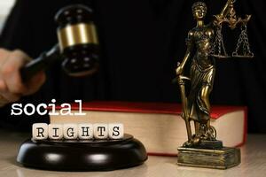 Word SOCIAL RIGHTS composed of wooden dices. Wooden gavel and statue of Themis in the background. photo