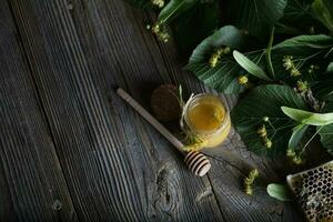 Linden blossoms honey in a glass bottle on a wooden surface. photo