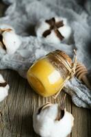 Cotton honey in a glass bottle on a wooden surface. photo