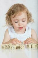 Small girl composes words from letters. Closeup photo