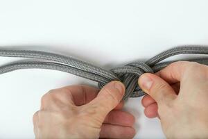 Rope with a simple knot on a white surface. Closeup. photo