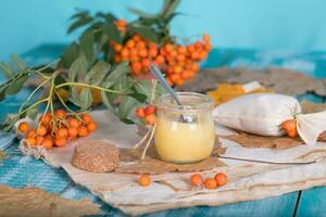 Rowan berries, glass with honey and honeycomb on a sackcloth. . photo