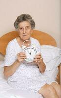 Old woman with vintage alarm clock photo