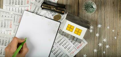 Blank sheet of paper and small paper house with coins on winter background. photo