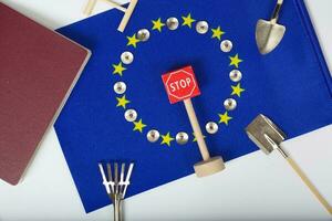 Agricultural tools,a card with access forbidden,pins,and a passport on an European flag.Closeup photo