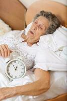 Old woman with vintage alarm clock photo