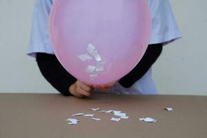 de cerca estudiante hacer Ciencias experimentar acerca de estático electricidad desde rosado globo y piezas de papel. concepto, Ciencias proyecto trabajo actividad. aprendizaje por haciendo. educación. foto