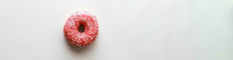 Banner Flat lay pink donut on color background. Dessert with icing photo