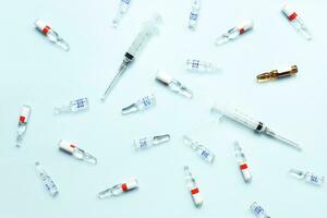 Pattern of ampoules and syringes. Vaccination. Bird flu. Covid 19. Flat lay ampoules and medicines on a blue background photo