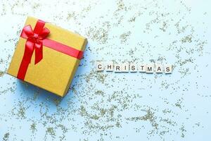 Flat lay Christmas gift on a blue background, sparkles. Word christmas from wooden letters photo