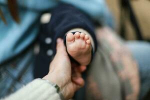 pequeño bebé pie. el mano sostiene el niño pierna. niños proteccion día foto