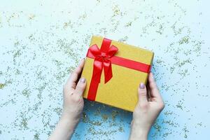 manos participación un regalo con un rojo arco. plano laico Navidad regalo foto