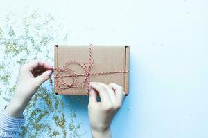 Wrap gifts. Flat lay christmas present. Hands holding a craft box with a bow photo