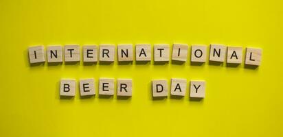 agosto 4, internacional cerveza día, minimalista bandera con el inscripción en de madera letras en un amarillo antecedentes foto