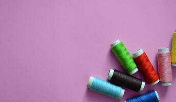 spools of thread on a pink background, a banner for an atelier, tailoring, sewing threads, a photo for a sewing workshop, a place for text