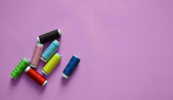 spools of thread on a pink background, a banner for an atelier, tailoring, sewing threads, photos for a textile factory, a place for text