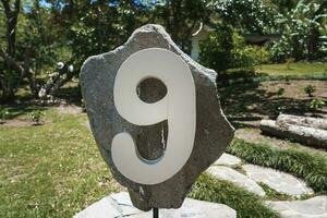 House number 9 installed on a big rock in the garden of residence photo