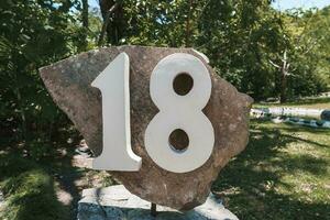 House number 18 installed on a big rock in the garden of residence photo