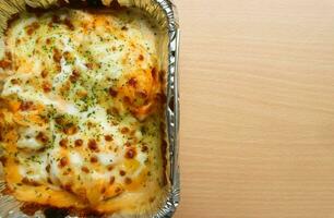 Pasta Makaroni Saus Keju or Pasta Mac and cheese in the aluminium foil bowl on the wooden background photo