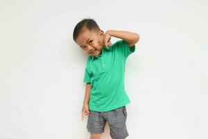 Portrait of a cheerful little Asian boy looking at camera while pointing in his cheek, isolated on the white background photo