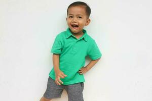 retrato de un contento pequeño asiático chico mirando a cámara mientras gritos en el blanco antecedentes foto