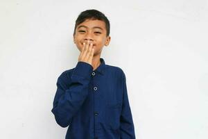 Smiling boy looking at camera while covering his mouth with hand in embarrassment photo