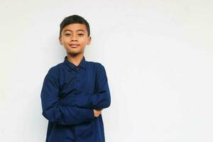 Smiling confident boy wearing blue casual shirt looking at the camera with arm crossed isolated on white background photo