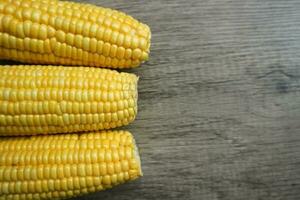 Sweet corn cob pile on wooden table with copy space. Maize ears group, autumn sweetcorn, corncob pile, yellow corn ear on wood rustic background photo