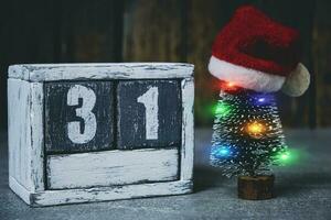 31 on calendar and a decorated Christmas tree with garland and Santa hat. photo