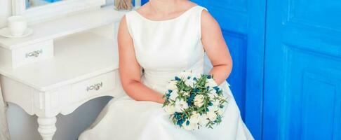 Luxury model sitting on chair with brides bouquet in studio photo