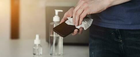 Man disinfecting phone with antiseptic wet wipe photo