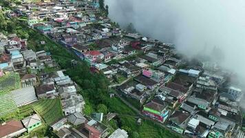 aéreo Visão do lindo colorida aldeias dentro Nepal furgão Java em montar somando, magolang, central Java, Indonésia. escondido Vila atrás nuvens e névoa em a declives do montar somando. video