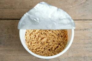 cooked instant cup noodle with ingredient on a brown wooden table photo