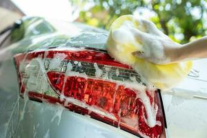 female hand with yellow sponge washing car photo