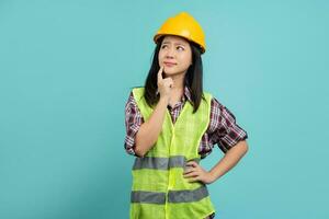 Portrait of thinking business Asian woman wearing builder helmet isolated on green. photo