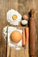 Orange carrot noodle dough bun, with ingredients on the table. photo
