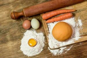 Orange carrot noodle dough bun, with ingredients on the table. photo