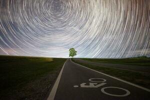 Lonely tree under the beautiful star trails in the starry night. photo