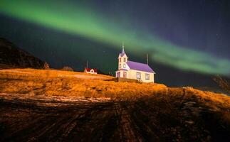 The beautiful Aurora Borealis over the church in Stodvarfjordur town in East Iceland. photo